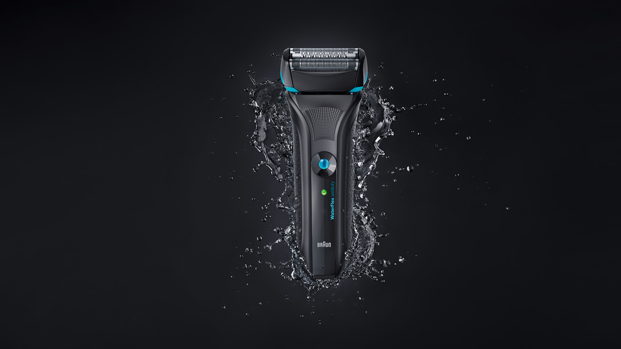 Black shaver on black background with water splash around it