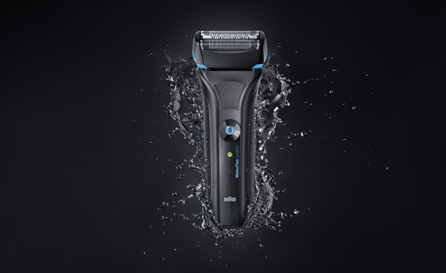 Black shaver on black background with water splash around it